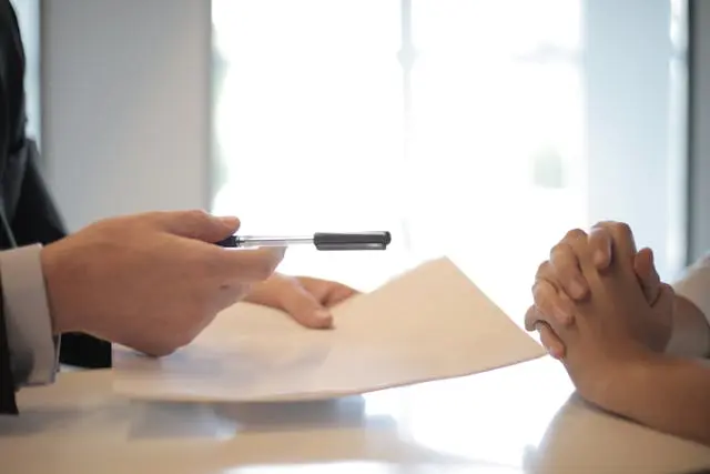 Close-up of a pet sitting contract being signed by a pet owner and sitter.
